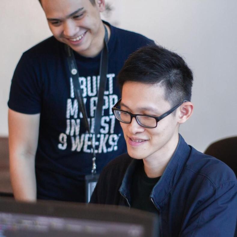 Two people looking at a computer screen and smiling